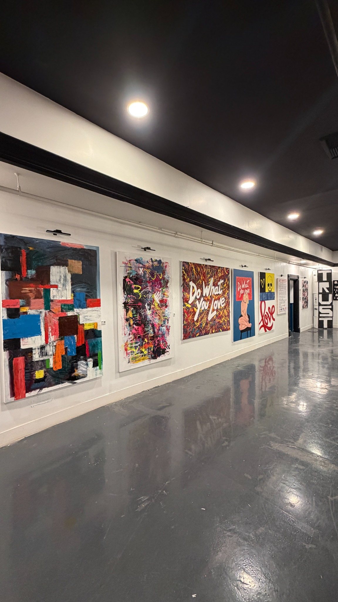 Contemporary paintings displayed along the gallery wall